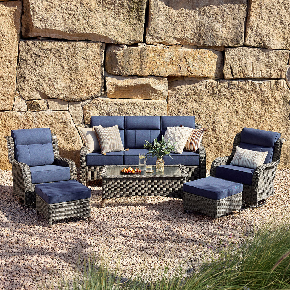 Outdoor 6 piece patio set with blue cushions against a stone wall.