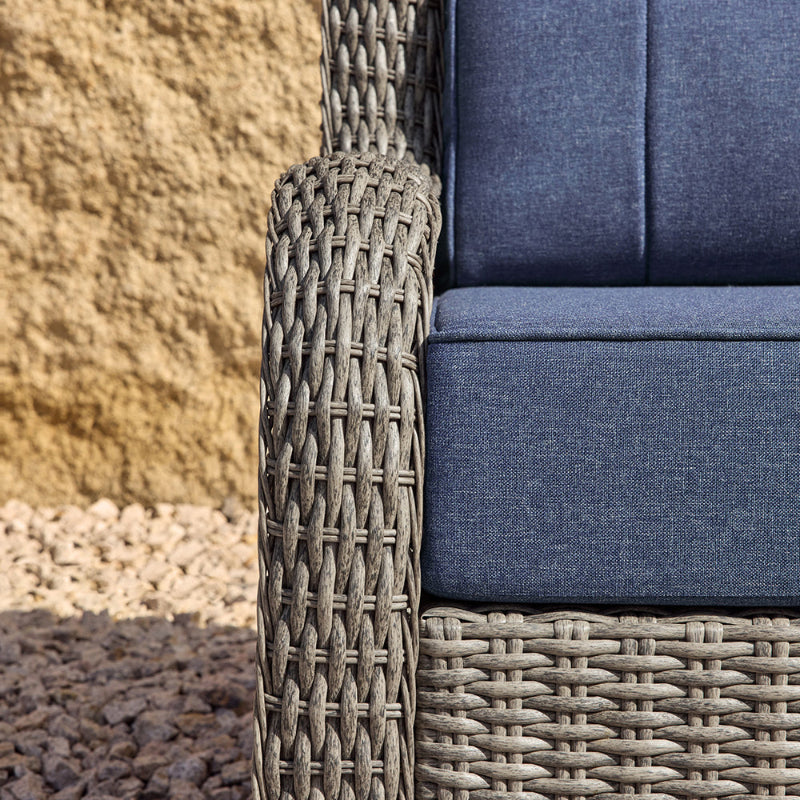 Wicker chair with blue cushions against a stone wall