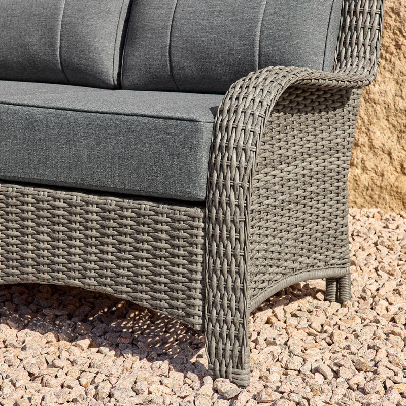 Gray wicker outdoor furniture with cushions on a gravel surface