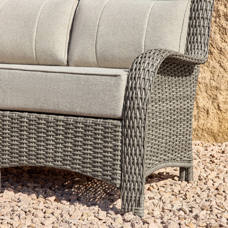 Gray wicker outdoor furniture with cushions on a gravel surface