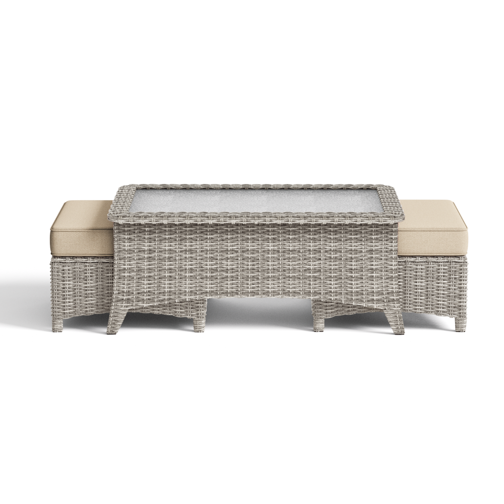 Wicker outdoor table with beige cushions on a white background