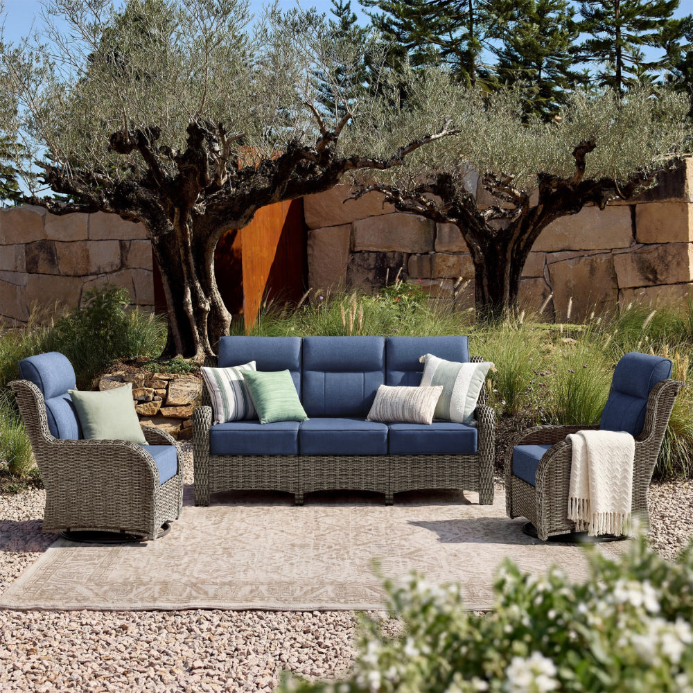 Outdoor 3 piece patio furniture set with blue cushions in a garden setting.