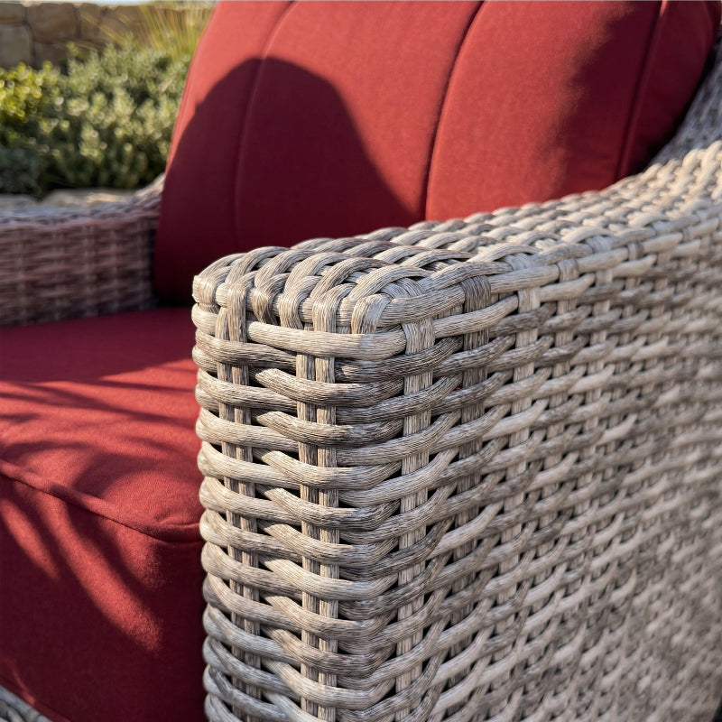 Close-up of a wicker chair with red cushions outdoors