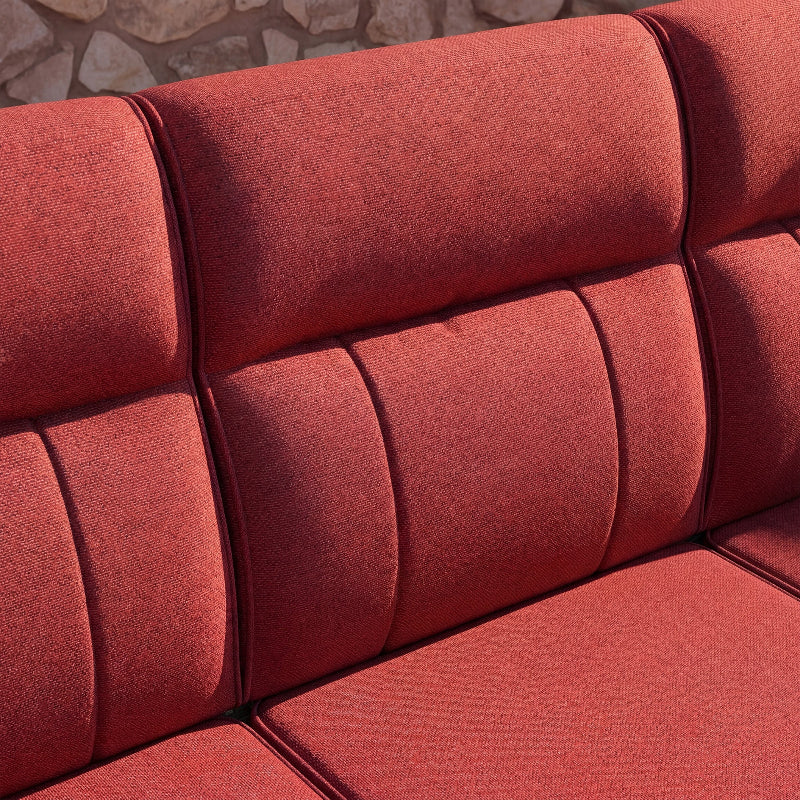 Close-up of a red textured sofa with a stone wall background