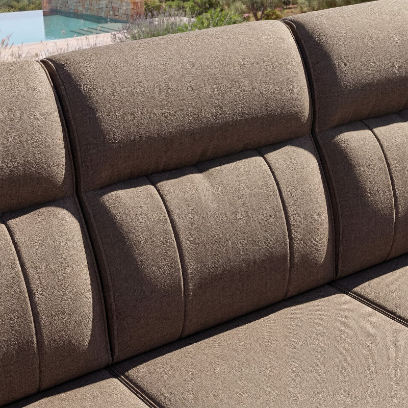 Brown outdoor sofa with a pool and garden in the background